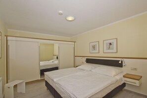 A bedroom with a bed, bedside table, nightstand, and a mirror.