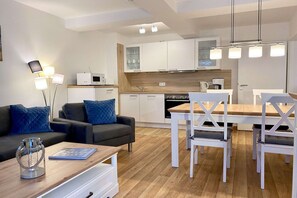 Una sala de estar moderna con sofá, una mesa de centro y una zona de comedor con sillas y una mesa.