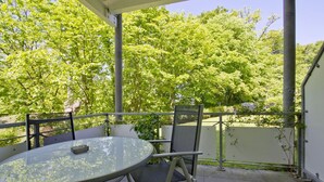 Un espace extérieur aménagé, abrité et doté de tables et de chaises, entouré de verdure et d’arbres.