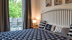 Een hotelkamer met een bed, een tafel en een stoel. Drie schilderijen hangen aan de muur.