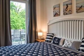 A hotel room with a bed, a table, and a chair. There are three paintings on the wall. - Close to the beach, balcony, AHOI adventure pool free of charge - Strandresidenz Brandenburg FeWo 36 (Göhren)