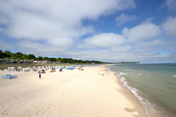 A beach with tents and people, a clear sky, and a calm sea. - Close to the beach, balcony, free AHOI adventure pool - Strandresidenz Brandenburg FeWo 04 (Göhren)
