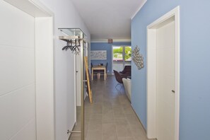 A hallway with a dining area, a coat rack, and a door leading to another room.