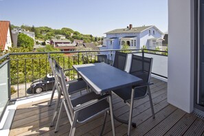 A balcony with a table and chairs, overlooking a residential area with houses and a parked car. - Die Ferienwohnung 05 in der Villa Anni - Villa Anni (Göhren)