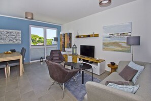 A modern living room with a TV, seating, and artwork.