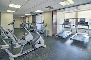 Une salle de sport équipée de tapis de course, d’appareils d’entraînement elliptique et de vélos d’exercice.