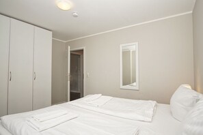 Une chambre à coucher comprenant un lit, une armoire, un miroir et une porte donnant sur une salle de bain.