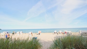 Ein Strand mit nummerierten Strandkörben und einem Sandweg zum Meer.