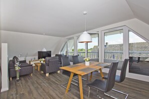 Ein modernes Wohnzimmer mit Essbereich, großen Fenstern und Blick ins Freie.