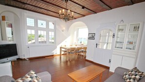 Ein geräumiges Wohnzimmer mit Holztisch, zwei Sofas, einem Fernseher und einem Essbereich mit Stühlen.