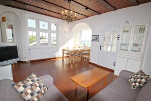 A spacious living room with a wooden table, two sofas, a TV, and a dining area with chairs. - Villa Hermine - fabulous villa in an idyllic location with sea views - Villa (Altefähr)