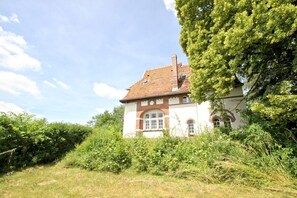 A traditional house with a tiled roof, surrounded by dense greenery and a clear sky. - Villa Hermine - fabulous villa in an idyllic location with sea views - Villa (Altefähr)