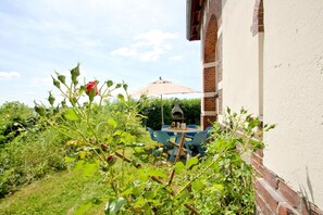 A garden with a brick wall, a blue table with chairs, and a red rose. - Villa Hermine - fabulous villa in an idyllic location with sea views - Villa (Altefähr)
