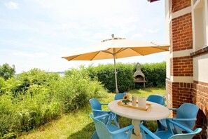An outdoor patio with a round table and blue chairs, an umbrella, and a brick wall. - Villa Hermine - fabulous villa in an idyllic location with sea views - Villa (Altefähr)