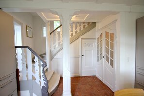 A staircase with white railings and a brick floor leading to a door with glass panels.