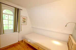 A small, single-bed room with a window, a radiator, and a wall-mounted shelf. - Villa Hermine - a fabulous villa in an idyllic location with a view of the sea - Villa (Altefähr)