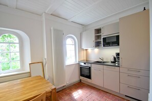 A compact kitchen with a wooden table, a built-in oven, a microwave, and a sink. - Villa Hermine - a fabulous villa in an idyllic location with a view of the sea - Villa (Altefähr)