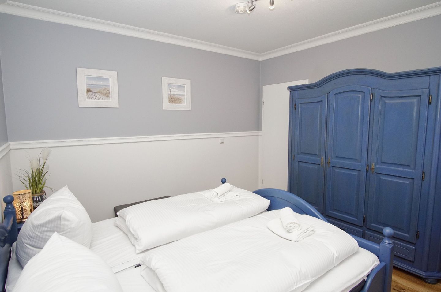 Ein Schlafzimmer mit zwei Betten, einem Kleiderschrank und zwei gerahmten Bildern an der Wand.