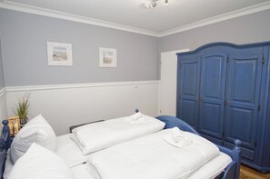 A bedroom with two beds, a wardrobe, and two framed pictures on the wall. - Panoramic apartment—with ocean views and a balcony, access to the pool and sauna— (Göhren)