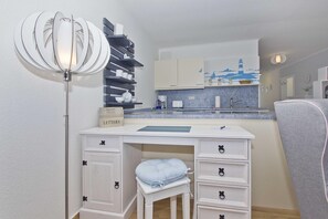 Ein gemütliches Schlafzimmer mit Schreibtisch, Stuhl, Nachttisch und Stehlampe.