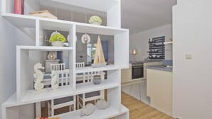 A modern kitchen with white cabinetry, a built-in oven, and a countertop. - Vacation apartment with balcony, use of swimming pool and sauna - Haus Strandeck FeWo 19 (Göhren)