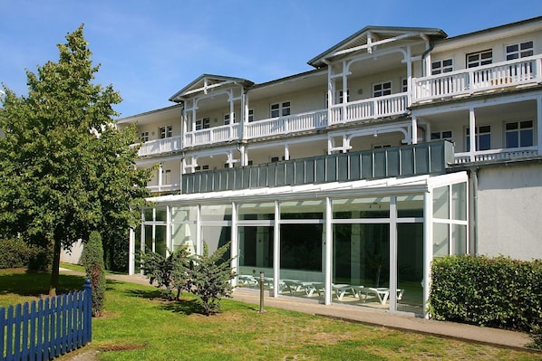 A multi-story hotel with balconies, large windows, and outdoor seating. - Die Ferienwohnung Nr. 14 im Haus Strandeck - Haus Strandeck (Göhren)