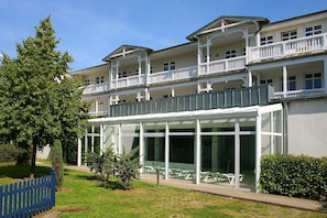 A multi-story hotel with balconies, large windows, and outdoor seating. - Die Ferienwohnung Nr. 14 im Haus Strandeck - Haus Strandeck (Göhren)