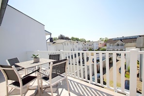 A balcony with a table and chairs, a potted plant, and a white fence. - Die Ferienwohnung Nr. 14 im Haus Strandeck - Haus Strandeck (Göhren)