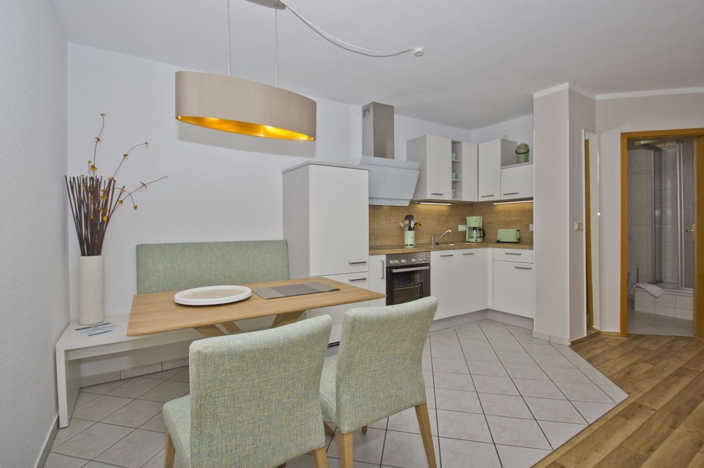 A modern kitchen with white cabinets, a wooden dining table, and two chairs.