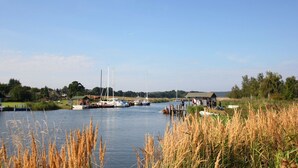 Une rivière paisible où sont amarrés des bateaux, un petit quai et une rive herbeuse.