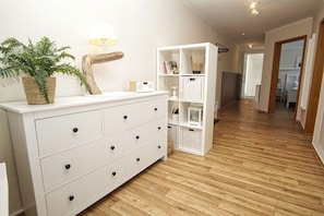 A hallway with a white dresser, wicker baskets, a lamp, and a bookshelf. - Die Ferienwohnung Nr. 20 im Haus Strandeck - Haus Strandeck (Göhren)