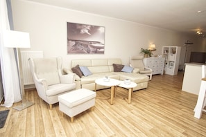 A modern living room with a sofa, armchair, ottoman, and two side tables. - Die Ferienwohnung Nr. 20 im Haus Strandeck - Haus Strandeck (Göhren)