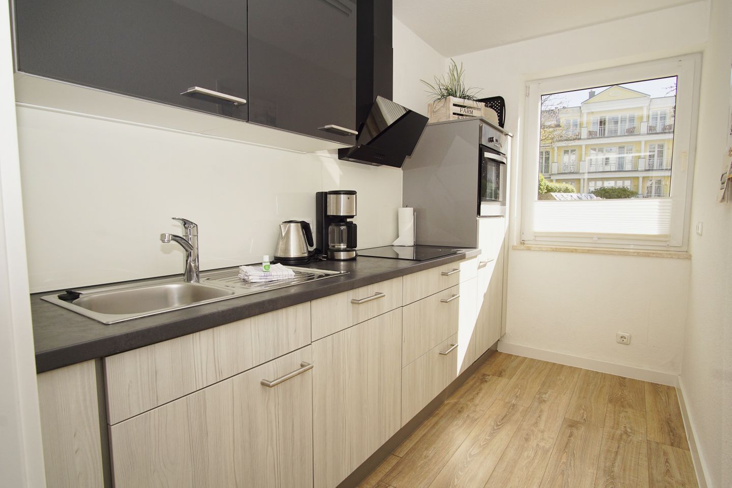 A modern kitchen with a stainless steel sink, a coffee maker, and a built-in oven.