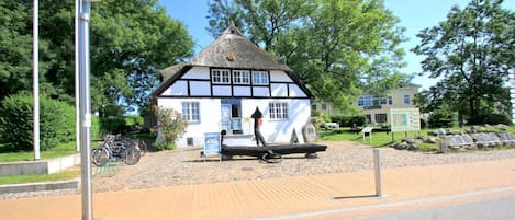 Ein traditionelles Gebäude mit einem Reetdach, einem Schild und einem Fahrrad davor.