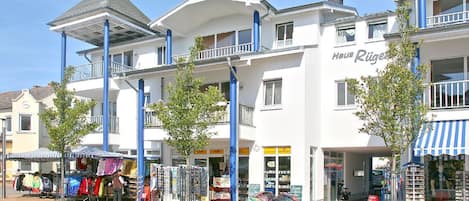 A row of white buildings with blue pillars, a covered outdoor market, and a sign for 'Haus Rige'.