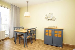 A dining area with a table and chairs, a hanging light fixture, a wall-mounted decorative piece, and a cabinet with a nameplate.