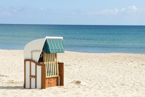 A beach chair with a striped awning on a sandy beach. - Haus Rügen - Holiday apartment with balcony, use of swimming pool and sauna - Haus Rügen (Göhren)