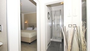 A hotel room with a bed, a shower, and a small bathroom. - FeWo Ostseeperle - with sea view and balcony, use of swimming pool and sauna - FeWo (Göhren)