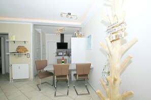 A modern kitchen with white cabinets, a built-in oven, and a dining area with two chairs and a table. - FeWo Ostseeperle - with sea view and balcony, use of swimming pool and sauna - FeWo (Göhren)