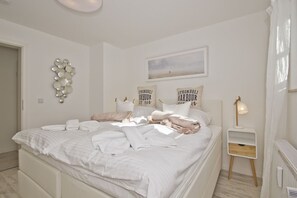 A neatly made bed with pillows and a blanket, a bedside table with a lamp, and a wall art piece above the bed.