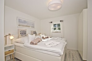 Une chambre à coucher avec un lit, une table de chevet, une lampe et une fenêtre avec des rideaux.