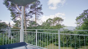 A balcony with a view of a body of water, surrounded by greenery and trees.