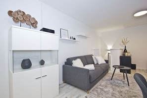 Una sala de estar moderna con un sofá gris, estantes blancos y una obra de arte de madera decorativa.