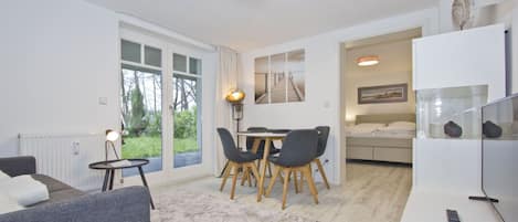Een moderne woonkamer met een bank, een eettafel met stoelen, een televisie en een open haard.