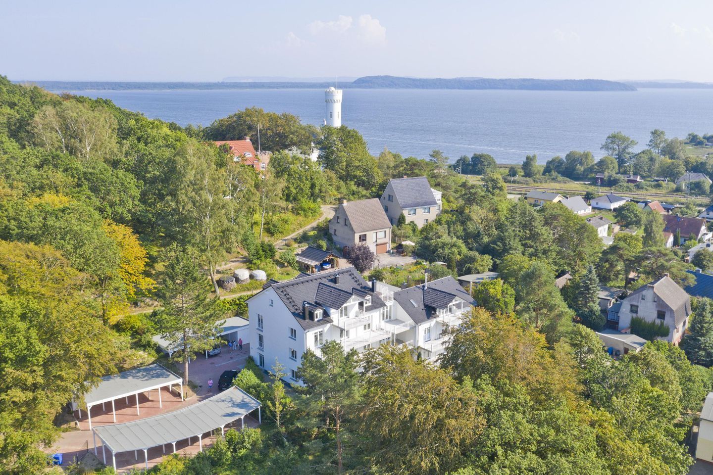 A residential area with houses, a tower, and a lake.