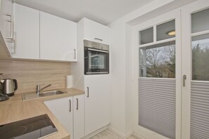 A modern kitchen with white cabinets, a stainless steel oven, and a wooden countertop.