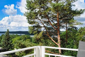 Un balcon doté d’une balustrade donnant sur un lac et des arbres.