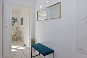 A hallway with a bench, a mirror, and a door leading to a bathroom.