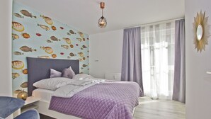 A bedroom with a bed, a headboard, a wall with fish patterns, a window with curtains, and a light fixture.