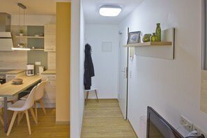 A compact kitchen with a dining area, a small seating space, and a TV. - Close to the beach, with a balcony; access to the pool and sauna - Strandhaus Mönchgut FeWo13 (Middelhagen)